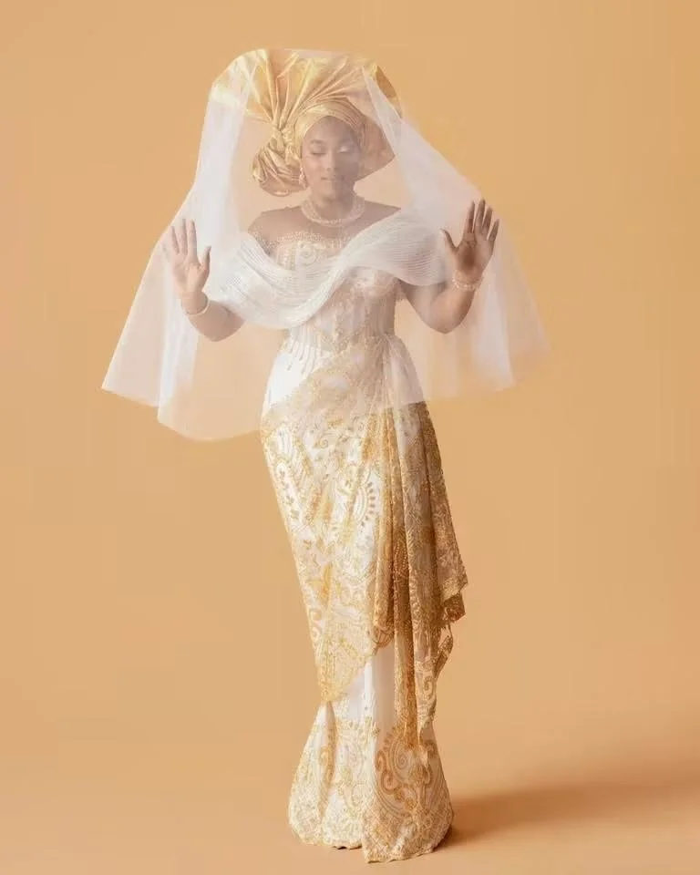 Mariée en dentelle ivoire et or soulevant son voile de tulle