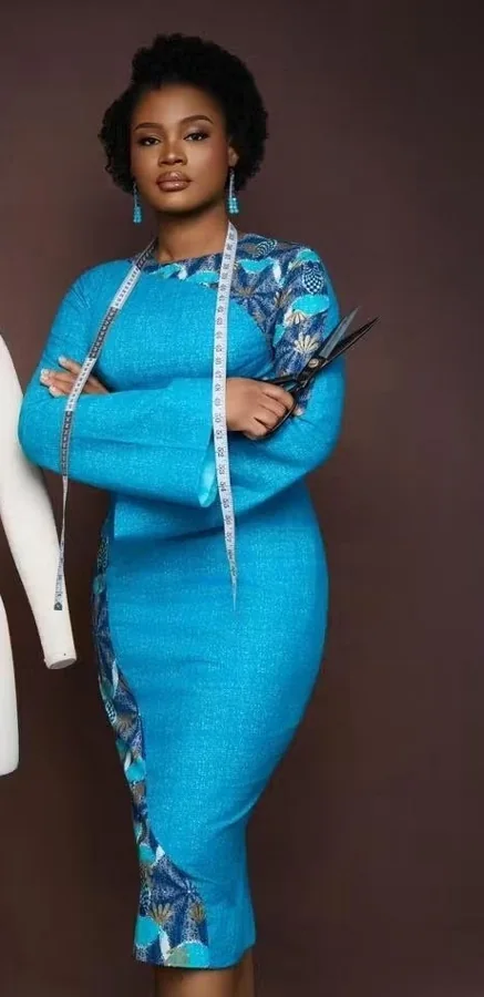 Couturière en robe turquoise, mètre ruban autour du cou et ciseaux en main
